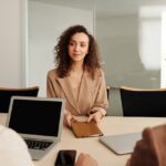 A woman in a business suit participates in a job interview, showcasing professionalism and modern office environment.